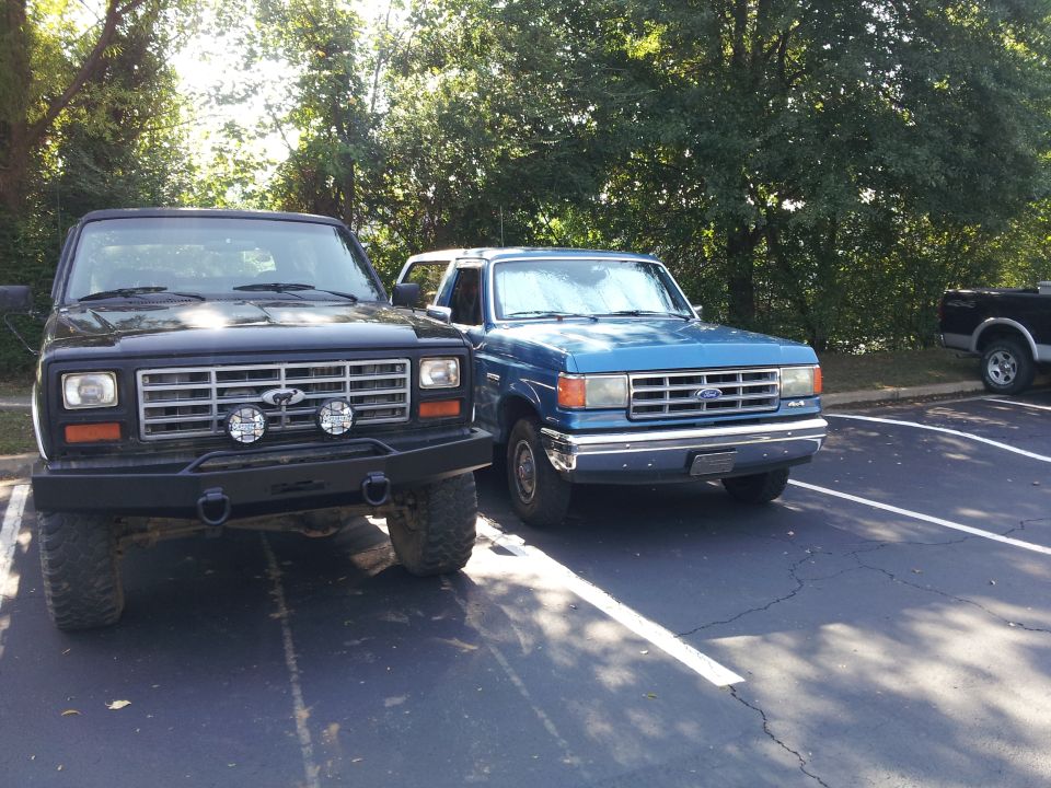 Black Bronco with aftermarket bumper and blue Bronco parked side-by-side