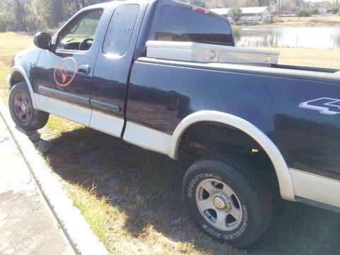 1986 Ford Bronco - This dark blue Ford F-150 pickup truck is shown from a 3/4 front angle, a toolbox in its bed.