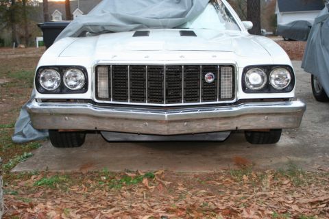 1976 Ford Ranchero - A white 1976 Ford Ranchero is parked outside, its front end covered by a car cover, revealing the grille and bumper.