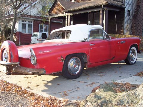 1956 Ford Thunderbird - A red 1956 Ford Thunderbird convertible with a continental kit is parked in a driveway.