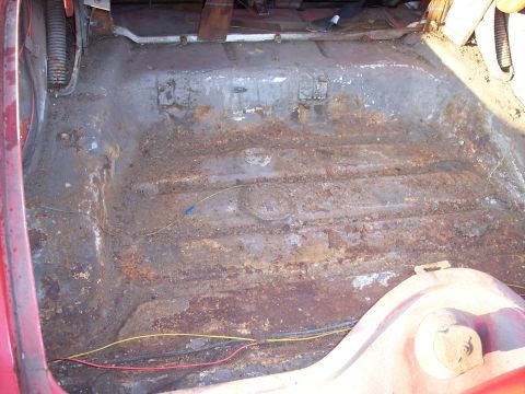 1956 Ford Thunderbird - Interior floor pan of a vehicle showing significant rust damage and exposed wiring.