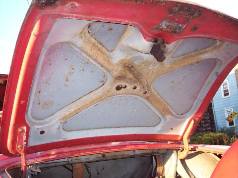 1956 Ford Thunderbird - The underside of a car hood displays significant rust and wear.