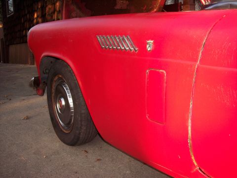 1956 Ford Thunderbird - Close-up of the fender on a red 1956 Ford Thunderbird, highlighting the distinctive chrome vent and emblem.