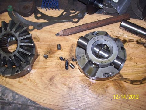 1990 Ford Bronco - Differential parts laid out on a wooden surface, with a pencil and other tools nearby.