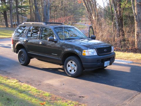 1991 Ford LTD Crown Victoria - A dark gray Ford Explorer is parked on a paved surface with trees in the background and the driver's door ajar.