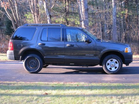 1991 Ford LTD Crown Victoria - Side view of a Ford Explorer SUV parked outdoors with a wooded area behind it.