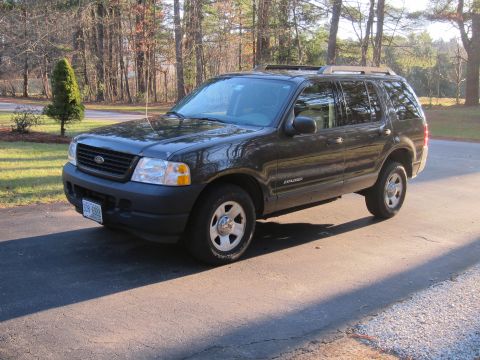 1991 Ford LTD Crown Victoria - This dark gray Ford Explorer SUV is seen from a three-quarter front view on a paved surface with trees in the background.