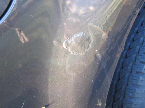 1991 Ford LTD Crown Victoria - The car's paint is damaged, showing rust and chips on the fender near the tire.