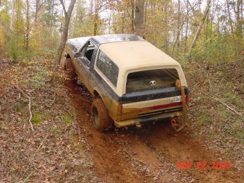 1989 Ford Bronco - Ford Bronco navigating a muddy path in a forest during autumn.