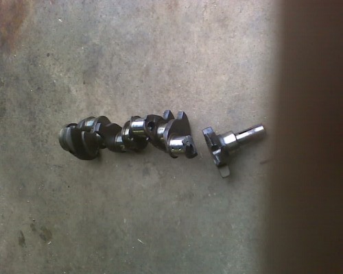 Crankshaft with five journals lying on a concrete surface