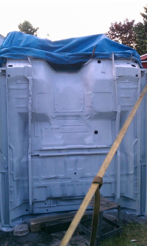 1994 Ford F-250 - The underside of a vehicle frame is visible, covered by a blue tarp and secured with a strap.