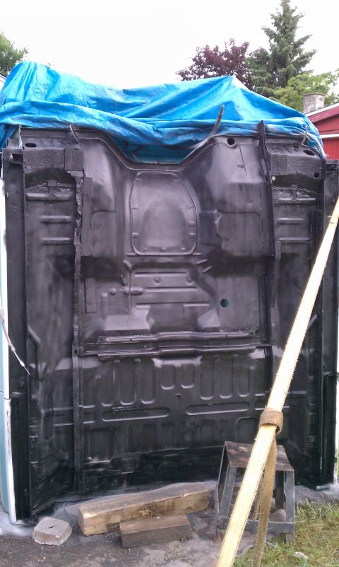 1994 Ford F-250 - Underside of a truck frame, possibly undergoing restoration, is visible with a blue tarp overhead.