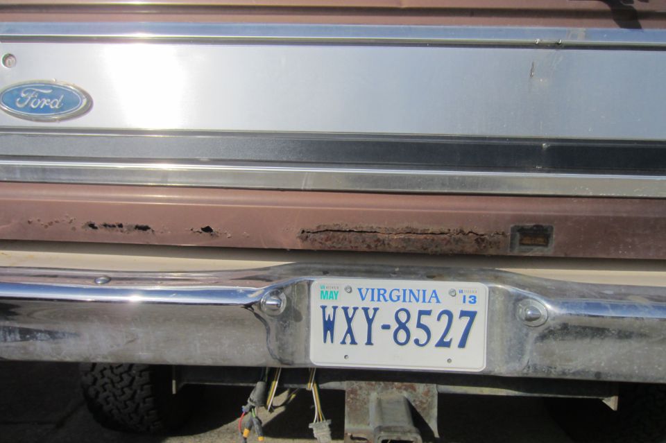 Rear tailgate of Ford with rust along lower edge, chrome bumper, Virginia plate WXY-8527