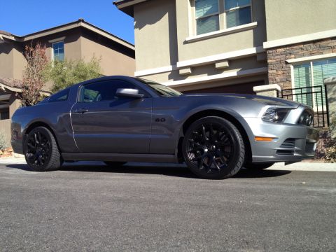 2013 Ford Mustang - A gray Ford Mustang with black rims is parked on a suburban street in front of a modern house.