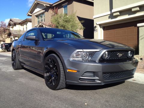 2013 Ford Mustang - A dark gray 2013 Ford Mustang coupe is parked on a residential street in front of a modern house.