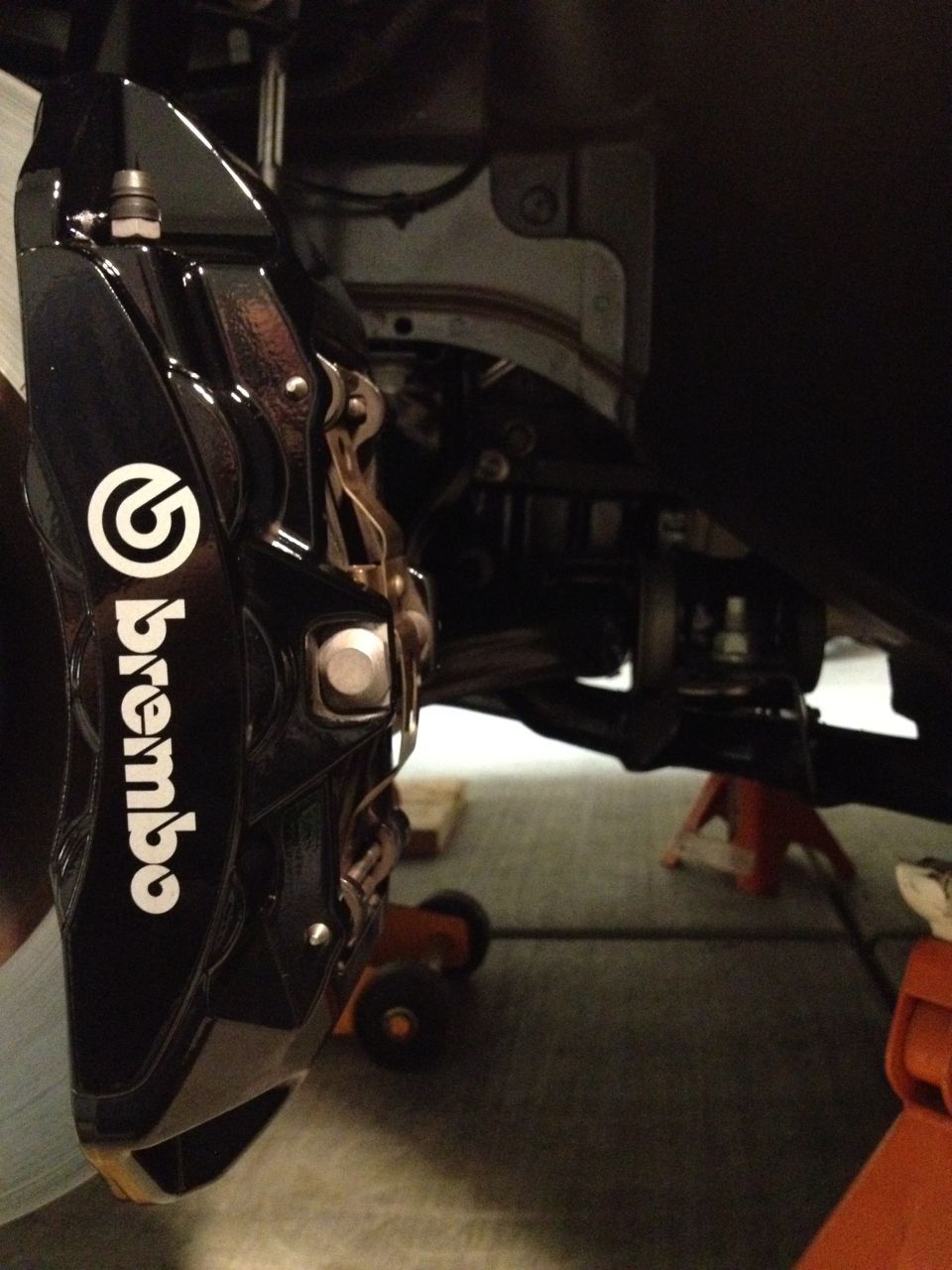 Brembo brake caliper mounted on suspension components, car on jack stands