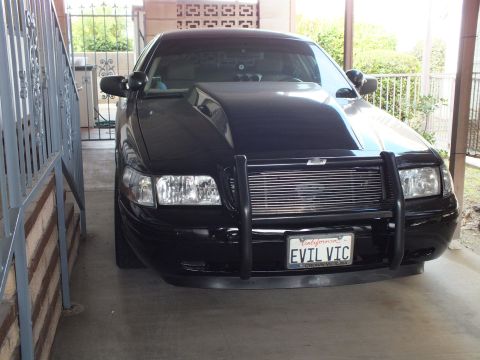 2003 Ford Crown Victoria - Front view of a black Crown Victoria with brush guard and EVIL VIC plate tucked into a residential carport