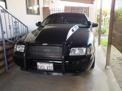 2003 Ford Crown Victoria - Crown Victoria nose with black push bar, billet grille and EVIL VIC plate parked beside a home staircase
