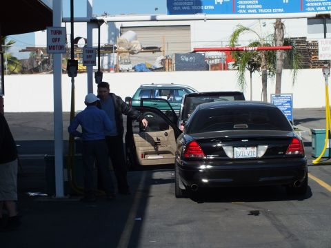 2003 Ford Crown Victoria - Rear of a black Crown Victoria at a car wash, door open and two attendants, Turn Off Motor signs overhead
