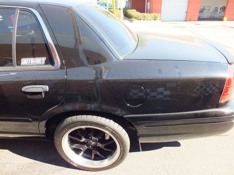 2003 Ford Crown Victoria - Rear three-quarter view of a black sedan with tinted glass, fuel door and a SUTA.NET decal on the C-pillar window.