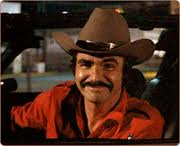 1989 Ford Bronco - A man with a mustache wearing a cowboy hat and a red shirt is seen inside a vehicle.