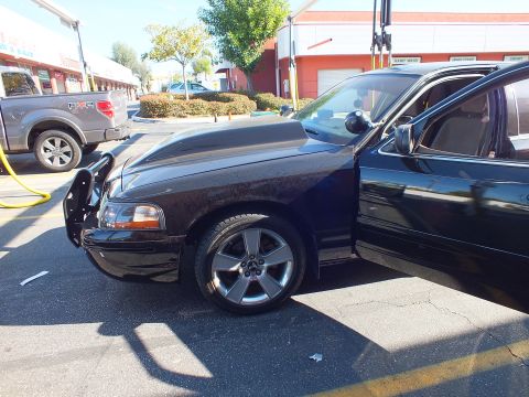 2003 Ford Crown Victoria - Front quarter of a lowered black sedan with cowl hood and gray five-spoke wheels beside a pickup.