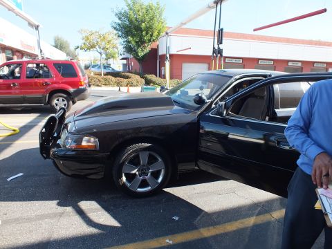 2003 Ford Crown Victoria - Lowered black four-door sedan with raised hood scoop, door open and attendant standing at right rear.