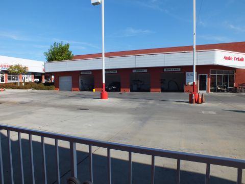 2003 Ford Crown Victoria - Exterior of a red auto-detail shop with multiple open bays behind a metal railing and clear blue sky.