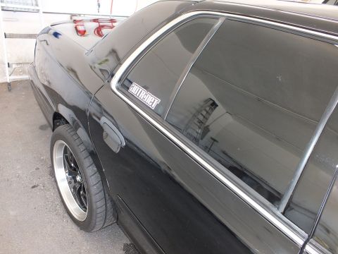 2003 Ford Crown Victoria - Rear-corner detail of a black sedan showing C-pillar decal, tinted glass and polished black wheel.