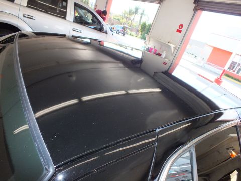 2003 Ford Crown Victoria - Overhead view across a freshly polished black car roof showing reflections of the open shop bays.