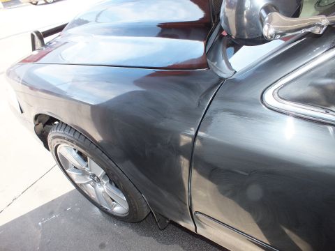 2003 Ford Crown Victoria - Dark gray sedan front fender and door panel showing paint swirl marks under direct light