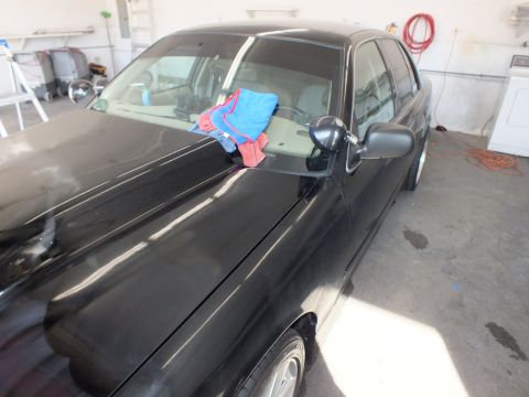 2003 Ford Crown Victoria - Hood and A-pillar of black sedan in shop, colored microfiber towels draped on glass