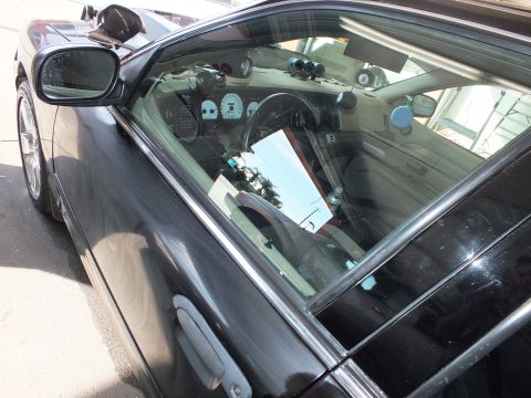 2003 Ford Crown Victoria - Interior of dark sedan seen through the door glass, gauge cluster and steering wheel visible