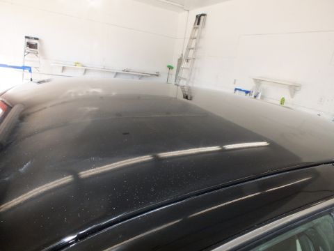 2003 Ford Crown Victoria - Top-down look at a dark sedan roof in a shop bay with a ladder against the wall