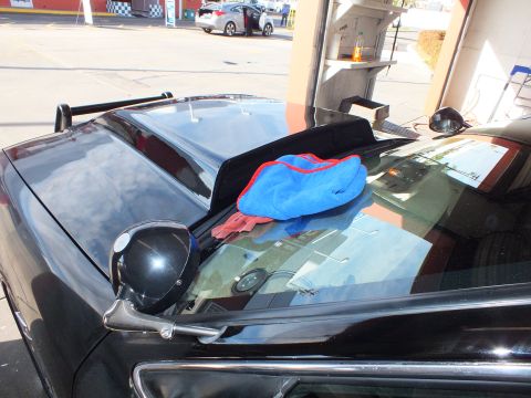2003 Ford Crown Victoria - Cowl and windshield of black sedan with microfiber towels, open shop door to the street
