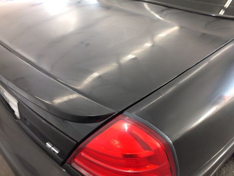 2003 Ford Crown Victoria - Detail of a dark gray decklid and red taillight covered in compounding swirl marks.