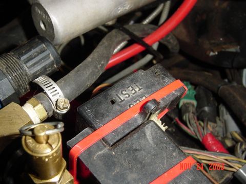 1989 Ford Bronco - A close-up view of a vehicle's engine compartment shows various wires, hoses, and a black electrical component with the word "TEST" visible.