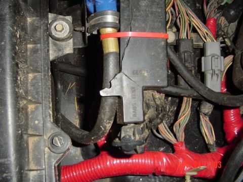 1989 Ford Bronco - Detail of a vehicle's engine bay wiring harness, showing a damaged electrical component and various hoses.