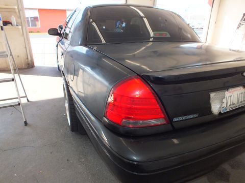 2003 Ford Crown Victoria - Polished dark gray sedan rear corner showing CROWN VICTORIA badge and California plate.