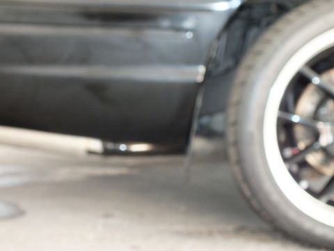 2003 Ford Crown Victoria - Low detail shot of a black car's lower body and a polished chrome-lip wheel with white wall.