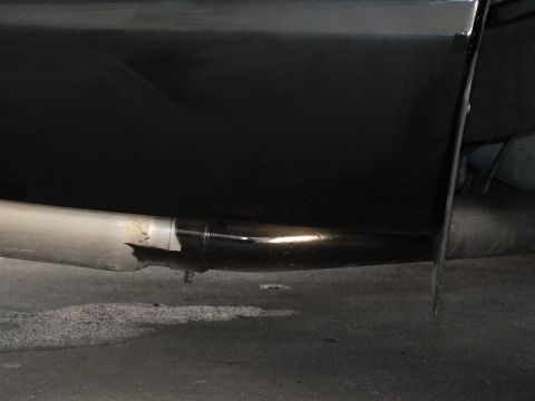 2003 Ford Crown Victoria - Underbody view of a polished exhaust system and tip beneath a black vehicle's lower body panel.