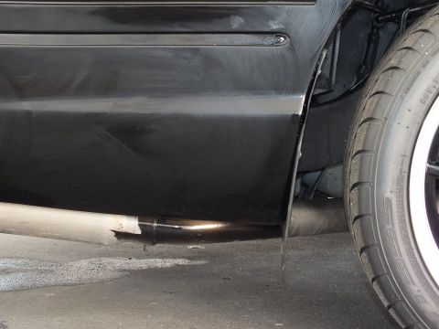 2003 Ford Crown Victoria - Rear exhaust outlet shown under a black car's rocker panel next to a whitewall tire.
