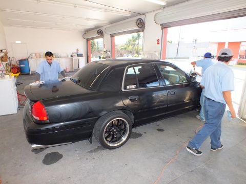 2003 Ford Crown Victoria - Lowered black Crown Victoria on dark five-spoke wheels gets detailed in a garage bay.