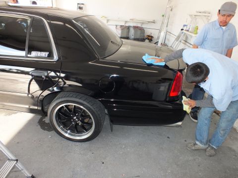 2003 Ford Crown Victoria - Two workers towel off the rear of a lowered black Crown Victoria in a shop bay.