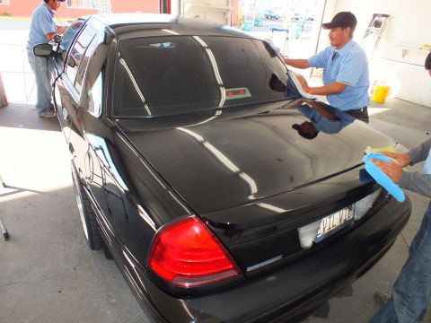 2003 Ford Crown Victoria - Workers dry the trunk of a black Crown Victoria with a vanity rear license plate.