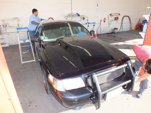 2003 Ford Crown Victoria - Detail shop crew works on a black Ford Crown Victoria sedan fitted with a tubular front push bar.