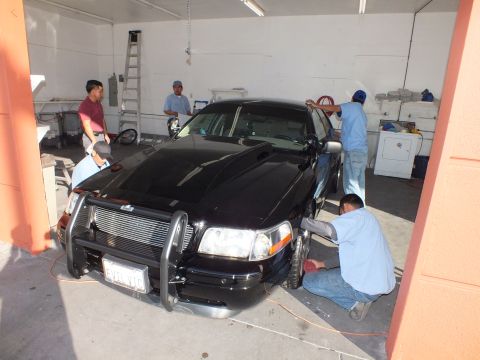 2003 Ford Crown Victoria - Black Crown Victoria with chrome grille guard and a California plate sits in a detail bay.
