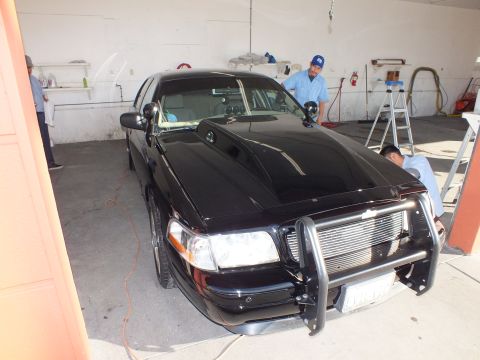 2003 Ford Crown Victoria - Glossy black Crown Victoria sedan with a tubular front push bar viewed from the side front.