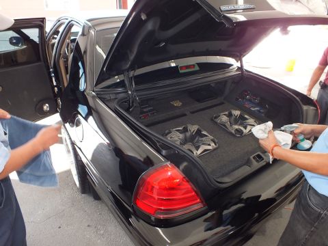 2003 Ford Crown Victoria - Open trunk of a black Crown Victoria reveals a carpeted enclosure with subwoofer speakers.