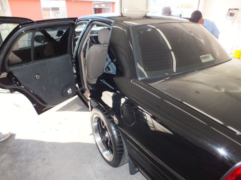 2003 Ford Crown Victoria - Driver side of a black Crown Victoria with rear door open showing tan cloth interior.